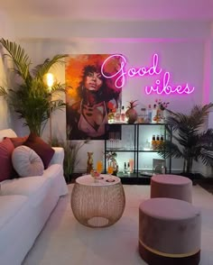 a living room filled with furniture and a neon sign above the couches that says good vibes