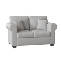 a white couch with two pillows on it's back and one arm facing the camera