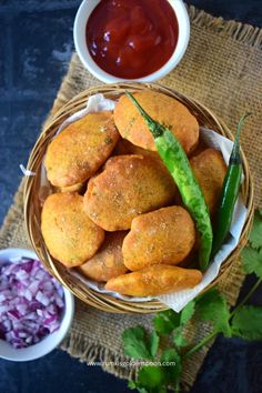 some fried food is in a bowl on a table with sauces and onion rings