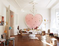 a heart shaped wall hanging above a dining room table with chairs and other furniture in front of it