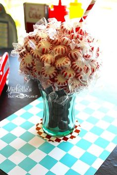 a glass vase filled with candy canes on top of a checkered tablecloth