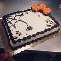 a decorated cake sitting on top of a metal counter next to a person's hand