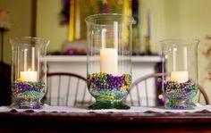 three candles are sitting on a table with glass vases