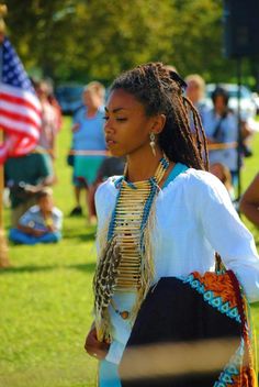 a woman with braids is standing in the grass