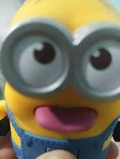 a close up of a person holding a minion in front of the camera with big eyes