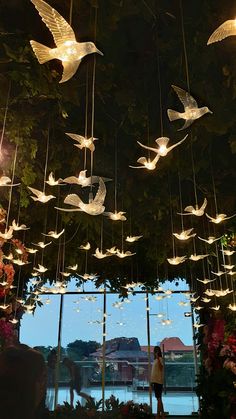 a room filled with lots of lights hanging from the ceiling and birds flying above it