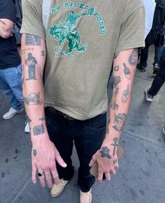 a man with many tattoos on his arm and hand is standing in front of a group of people