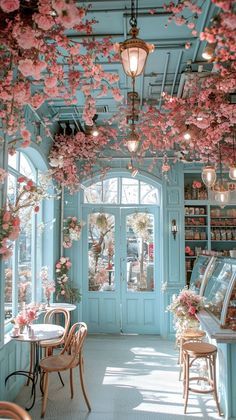 the inside of a restaurant with tables, chairs and flowers hanging from the ceiling above