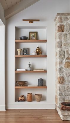 a stone fireplace in a living room with wooden shelves