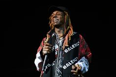 a man with dreadlocks on his head holding a microphone and wearing a scarf