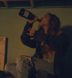 a woman sitting on the floor drinking from a bottle