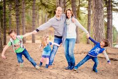 a family is posing for a photo in the woods with their arms around each other