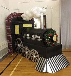 a black and white train is on the floor next to a brick wall with balloons