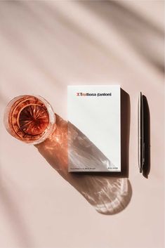 a book and pen sitting on top of a table next to a glass of wine