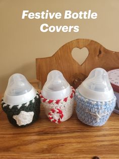 three baby bottles sitting next to each other on top of a wooden table with the words festive bottle covers