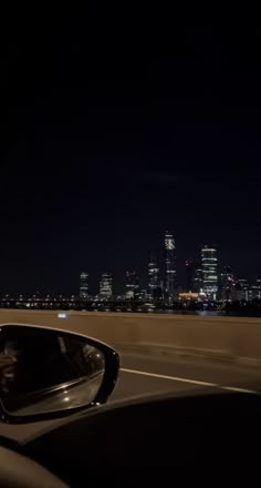 a car driving down the road at night with city lights in the backgroud