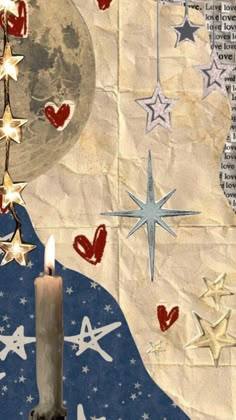 a lit candle sitting on top of a piece of paper with stars hanging from it