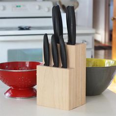 a wooden block holding knives on top of a counter next to a bowl and stove