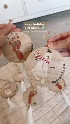 two people are holding wooden ornaments with hand prints on them and one has a snowman ornament that says easy holiday gift idea