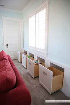 a living room with red couch and white cabinets