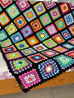 a crocheted granny blanket on a wooden bench