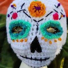 a white crocheted skull with multicolored flowers on it's face