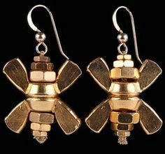 two pairs of earrings with gold and silver accents on black background, one is shaped like a flower