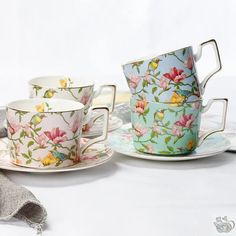 three tea cups and saucers with flowers on them, sitting next to each other