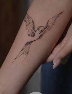 a woman's arm with a bird tattoo on it