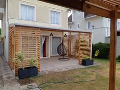 a wooden pergolan in front of a house with an attached patio and deck