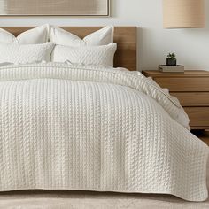 a bed with white quilts and pillows in a bedroom