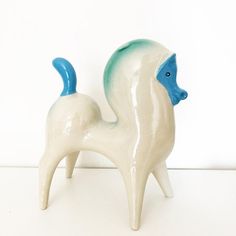 a white and blue ceramic horse on a white surface with a white wall in the background