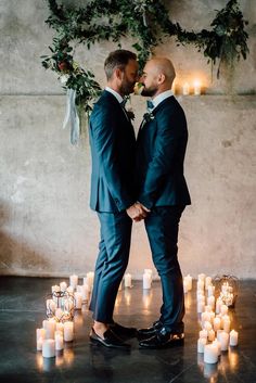 two men standing next to each other in front of candles