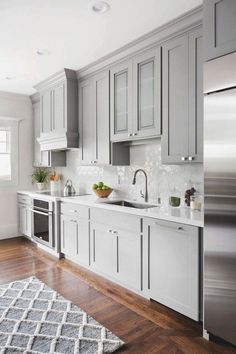 a kitchen with gray cabinets and white counter tops, hardwood floors, and stainless steel appliances