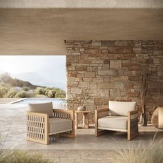 two chairs and a table in front of a stone wall