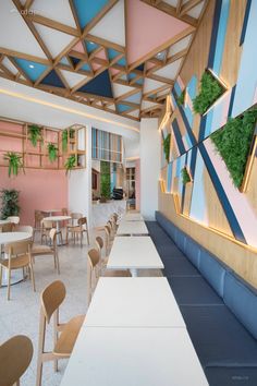 the interior of a restaurant with tables, chairs and plants on the wall above them