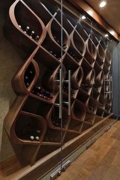 a wine rack in the corner of a room next to a glass wall with bottles on it