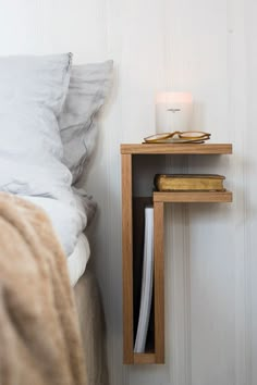 a small wooden shelf next to a bed