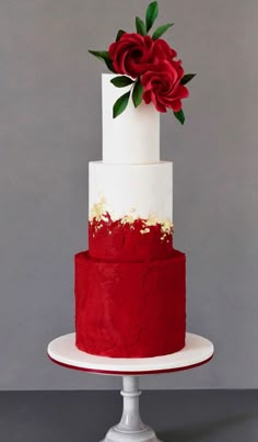 a red and white wedding cake with flowers on top