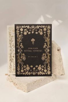 a black and white book sitting on top of a marble block with gold trimming