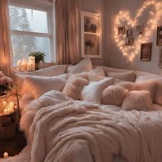 a bed with white pillows and blankets in a room decorated with lights, candles and pictures on the wall