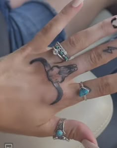 a woman's hand with two rings on it and an elephant tattooed on the middle finger