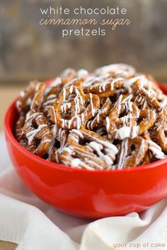 a red bowl filled with white chocolate cinnamon sugar pretzels on top of a table