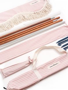 the pink and white striped case is filled with pencils, brushes, and other items