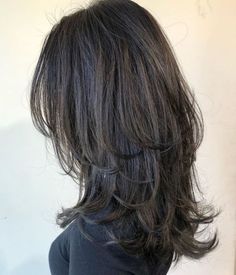 the back of a woman's head with long, wavy hair and black shirt