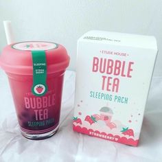 a pink bubble tea cup next to a box of strawberry flavored bubble tea on a bed