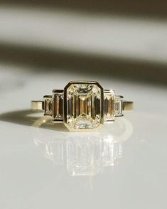 an engagement ring with three baguets on the side and two diamonds in the middle