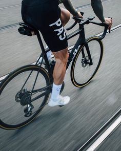 a man riding a bike down a street with no shoes on the front and side