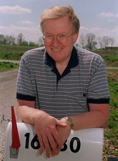 an older man sitting in front of a mailbox with his hands on the handle