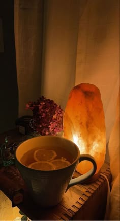 a cup of tea sitting on top of a wooden table next to a himalayan lamp